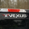 Raised vinyl dome Vexus decal on rear vehicle panel, straight-on view